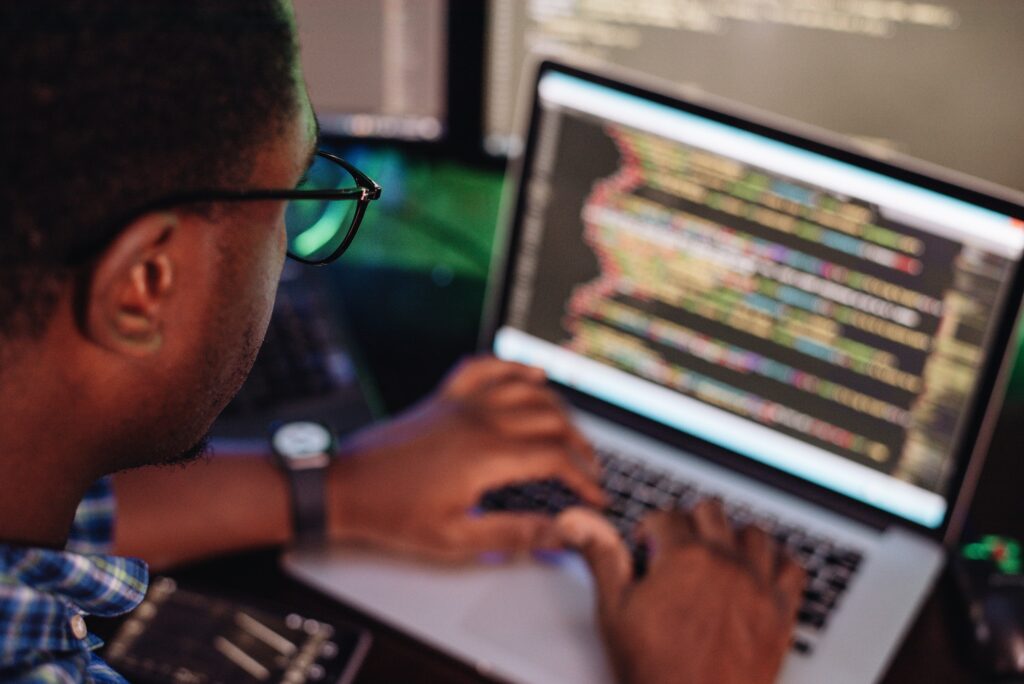 Black male in front of computer screen coding mobile app, web development, computer programming