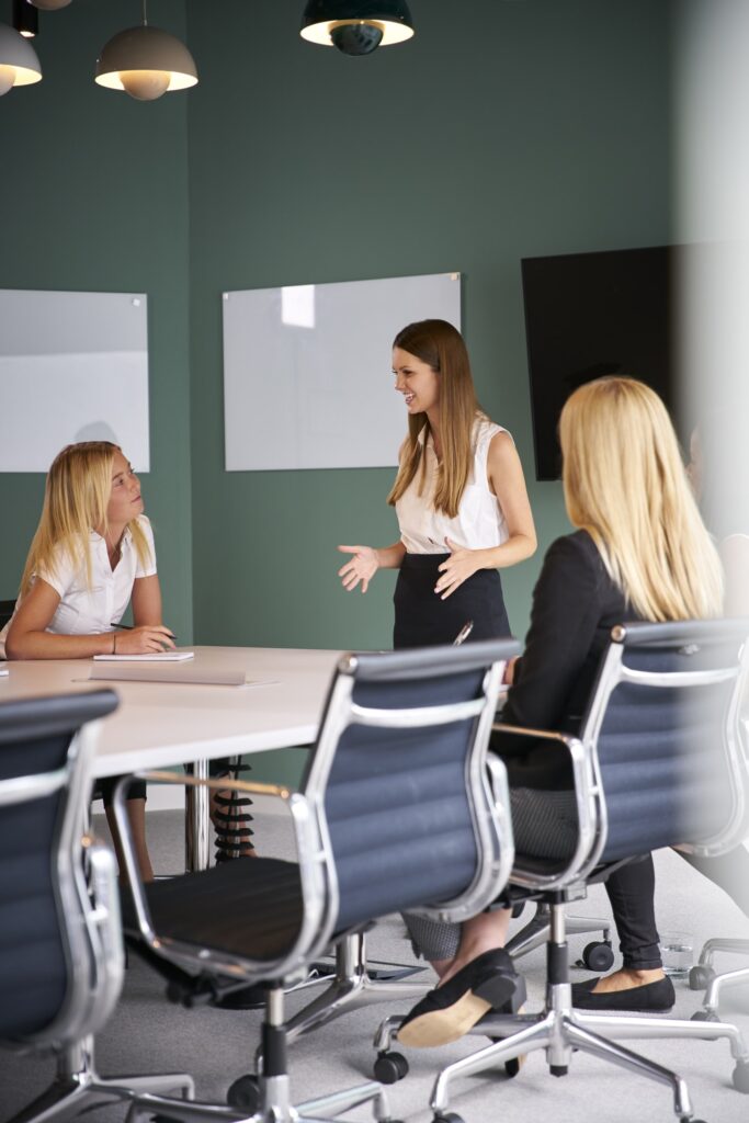 Group Of Businesswomen Sitting Around Boardroom Table And Collaborating On Task